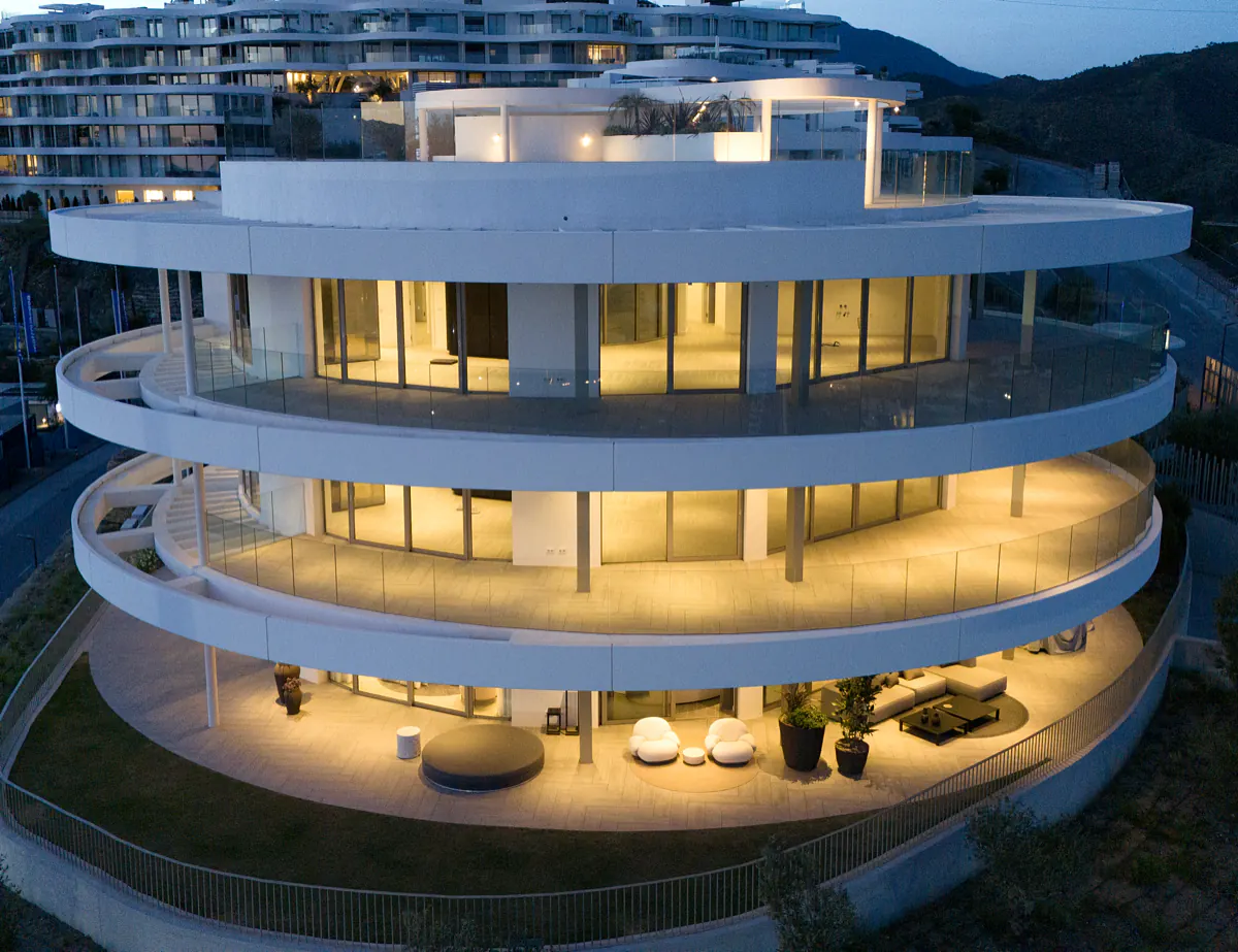 The circular building at dusk, every floor lit